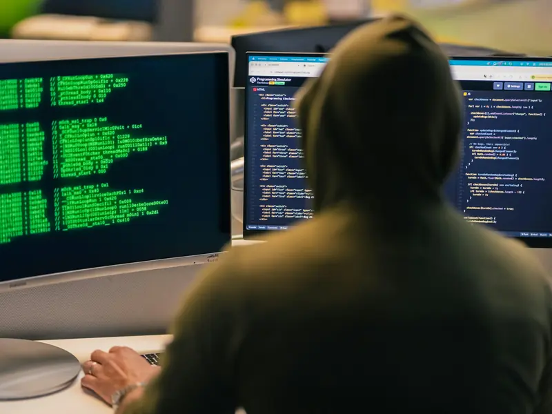 A security analyst with code and log output on the screens